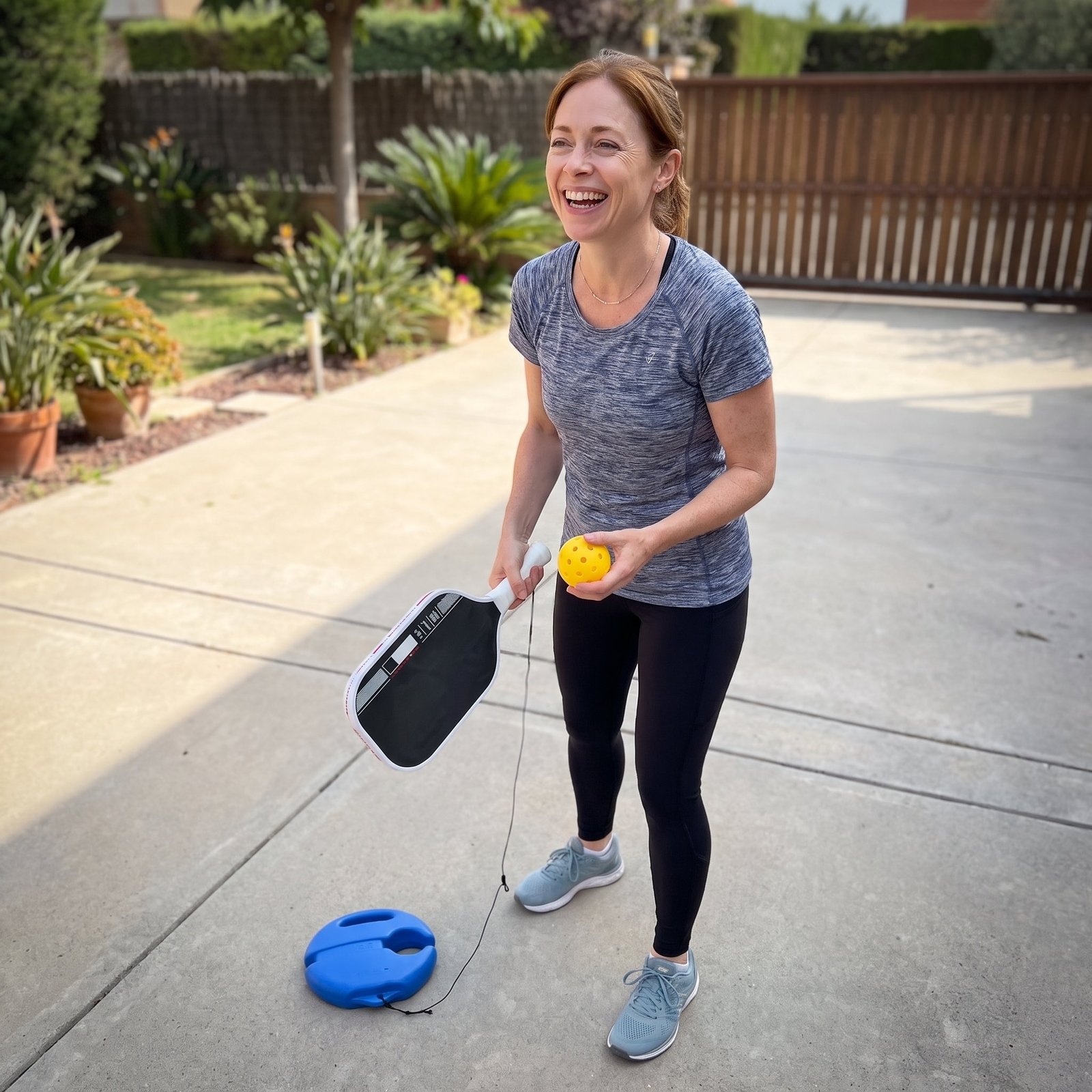 Woman practicing with the Pickleball At Home Kit in a driveway